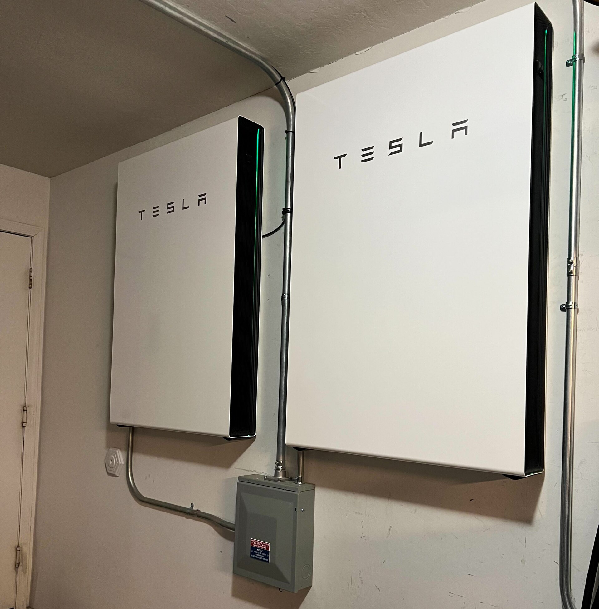 Two wall-mounted Tesla home batteries; illustrative equipment example.