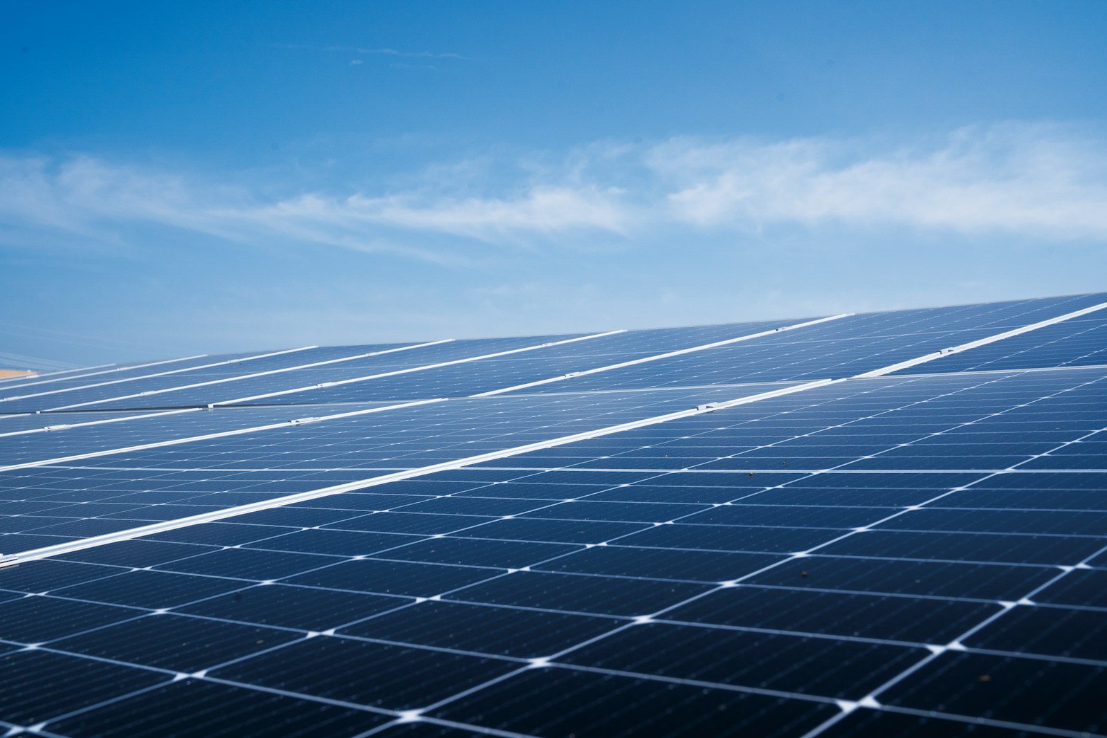 Solar photovoltaic panels beneath a blue sky; illustrative array detail.